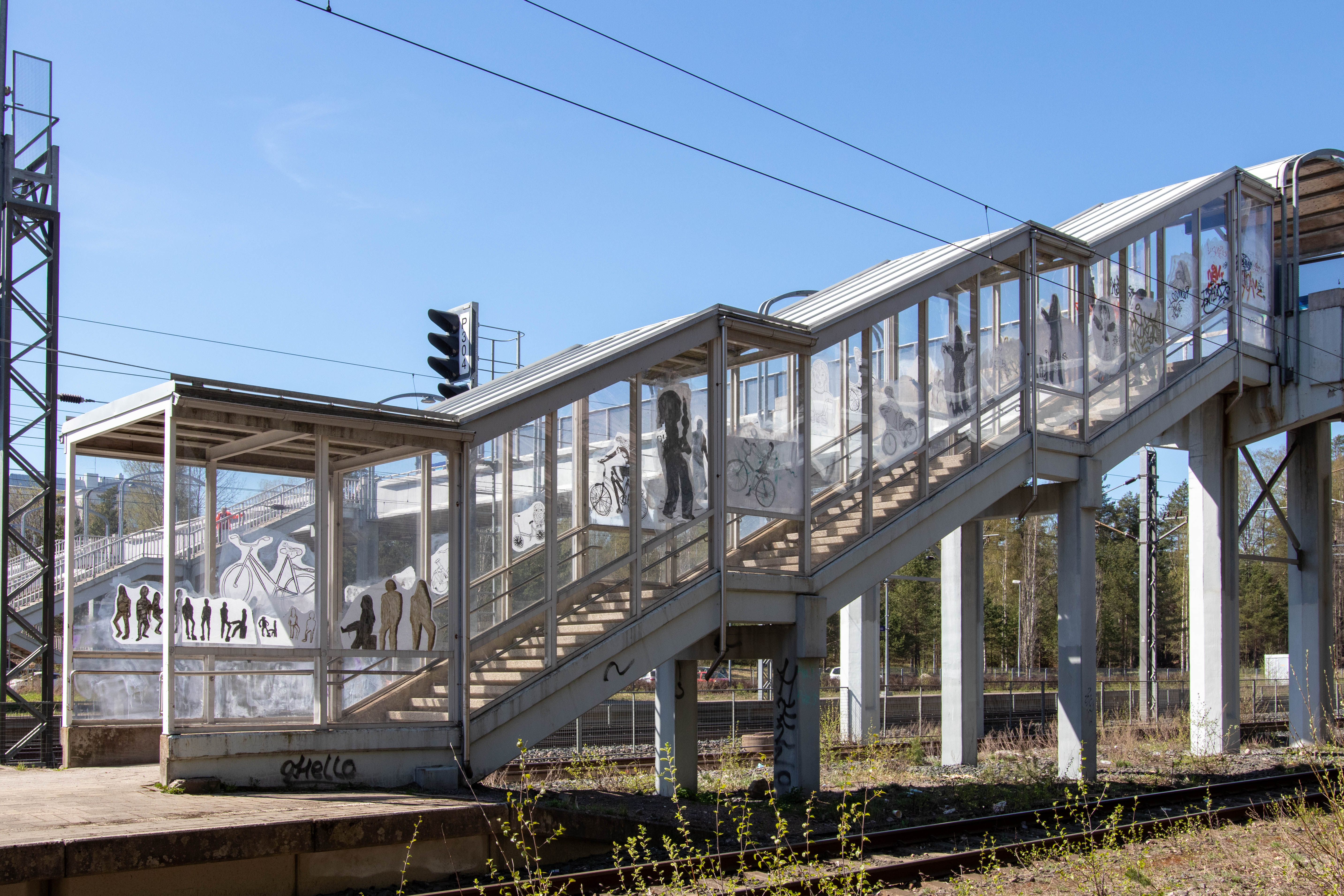 Kuvassa rautatieasemalaiturille laskevat rappuset, jonka lasiseiniin on kiinnitetty oppilaiden töitä