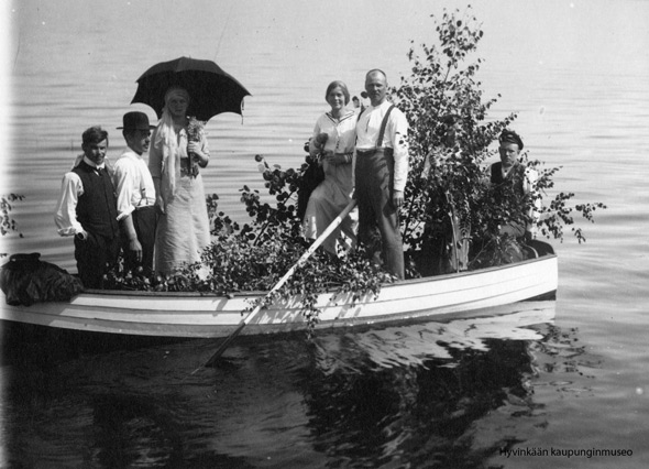 Mustavalkoisessa kuvassa ihmisiä soutuveneessä.