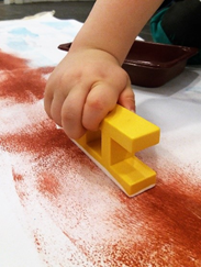 kuvassa lapsi painaa jälkiä paperiin palikalla
