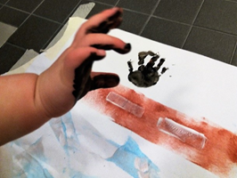 kuvassa lapsen käsi ja sen jälki mustana paperille painettuna