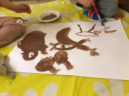kuvassa lapsi maalaa ruskealla maalilla paperiin
