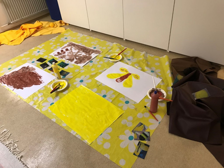 kuvassa on lasten valiita keltaisella ja ruskealla värillä maalattuja töitä