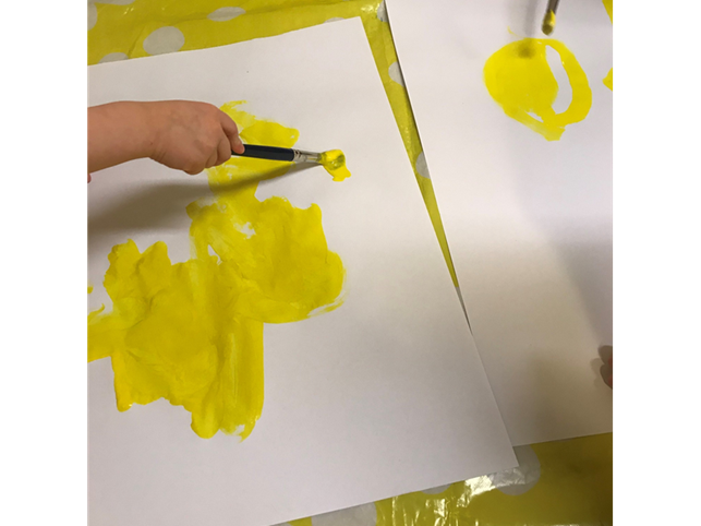 kuvassa lapsi maalaa keltaisella värillä paperiin
