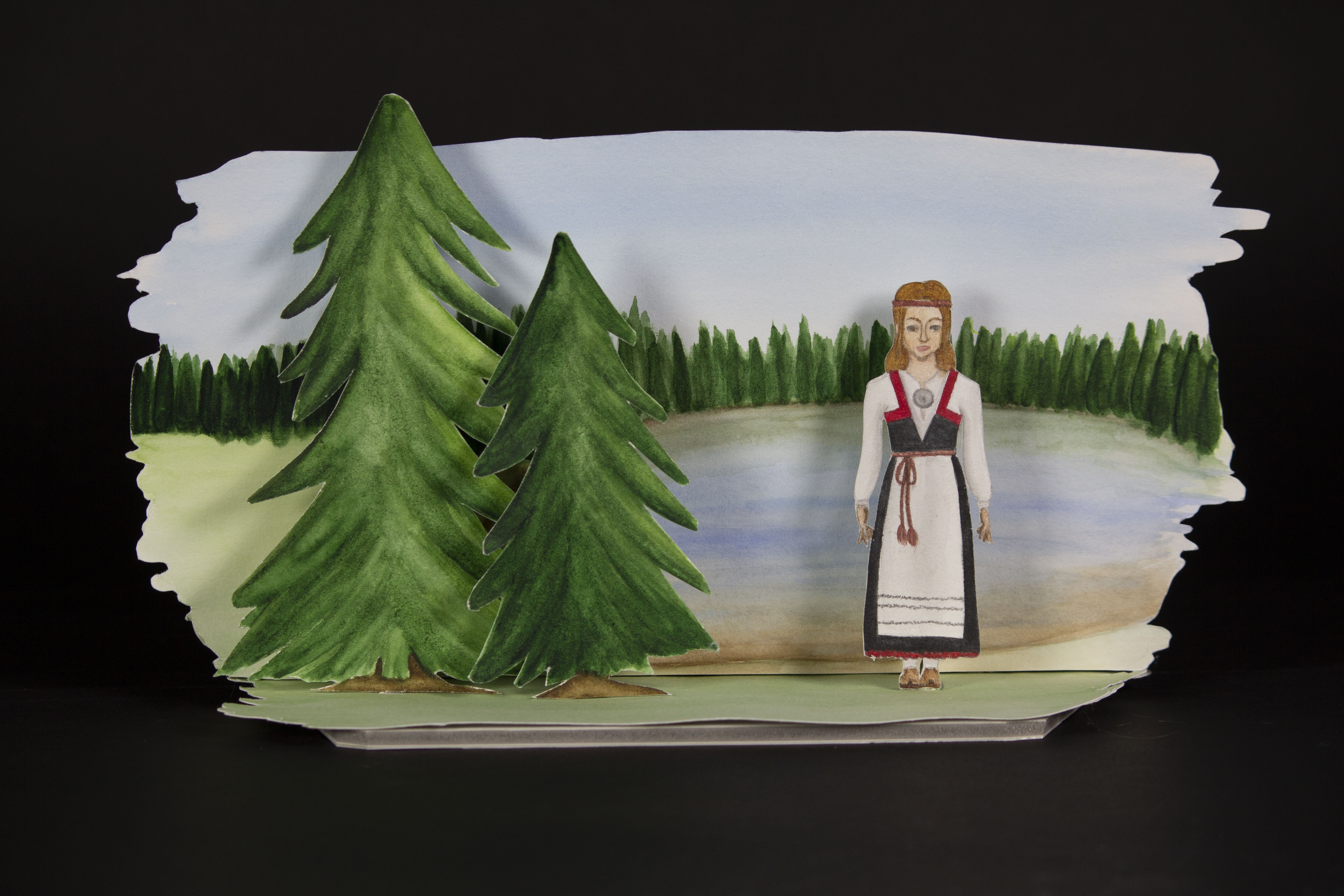 kuva 3d taideteoksesta, jossa on maisema suomesta. Horisontissa näkyy kuusipuita ja järvi. Teoksen edessä on kaksi kuusipuuta ja henkilö suomen kansallispuvussa.