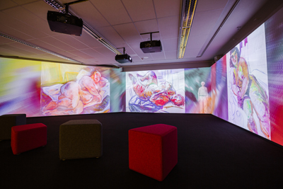 Näkymä digitaalisesta installaatiosta. Esillä kolme Saarisen kookasta alastonmaalausta ja väriliukumia. 