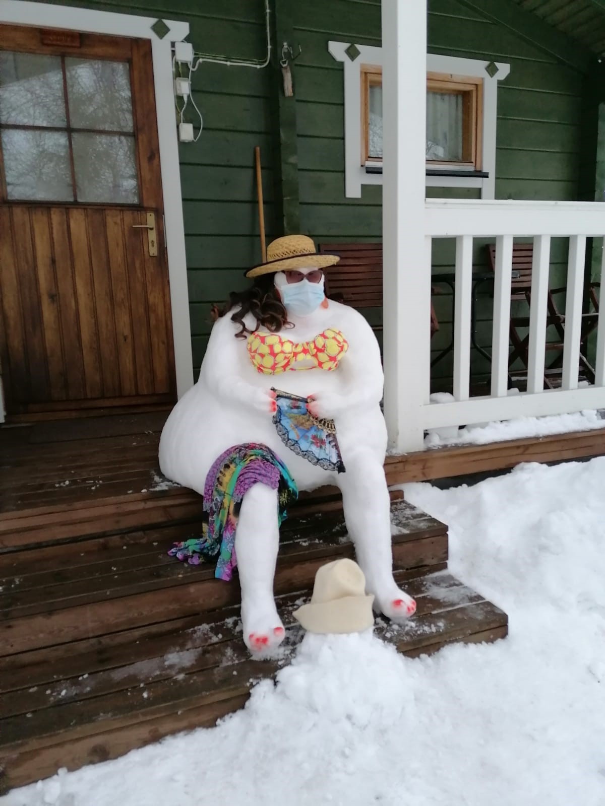 Kuvassa lumesta tehty nainen istuu portailla