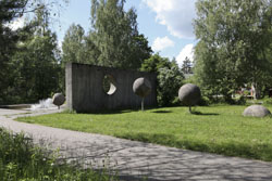 Kuva Liikettä tilassa patsaasta, jossa kivet menossa betoniseinässä olevan rei´än toiselle puolelle