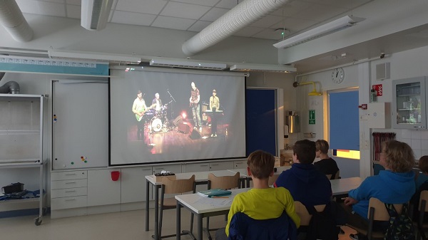 oppilaita luokassa katsomassa konserttia valkokankaalta