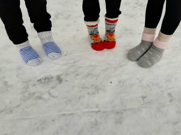 kolme oppilasta lumella villasukissa