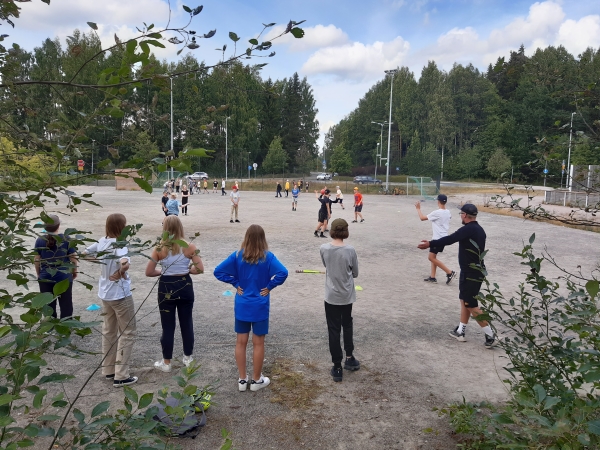 oppilaita pelaamassa pesäpalloa hiekkakentällä