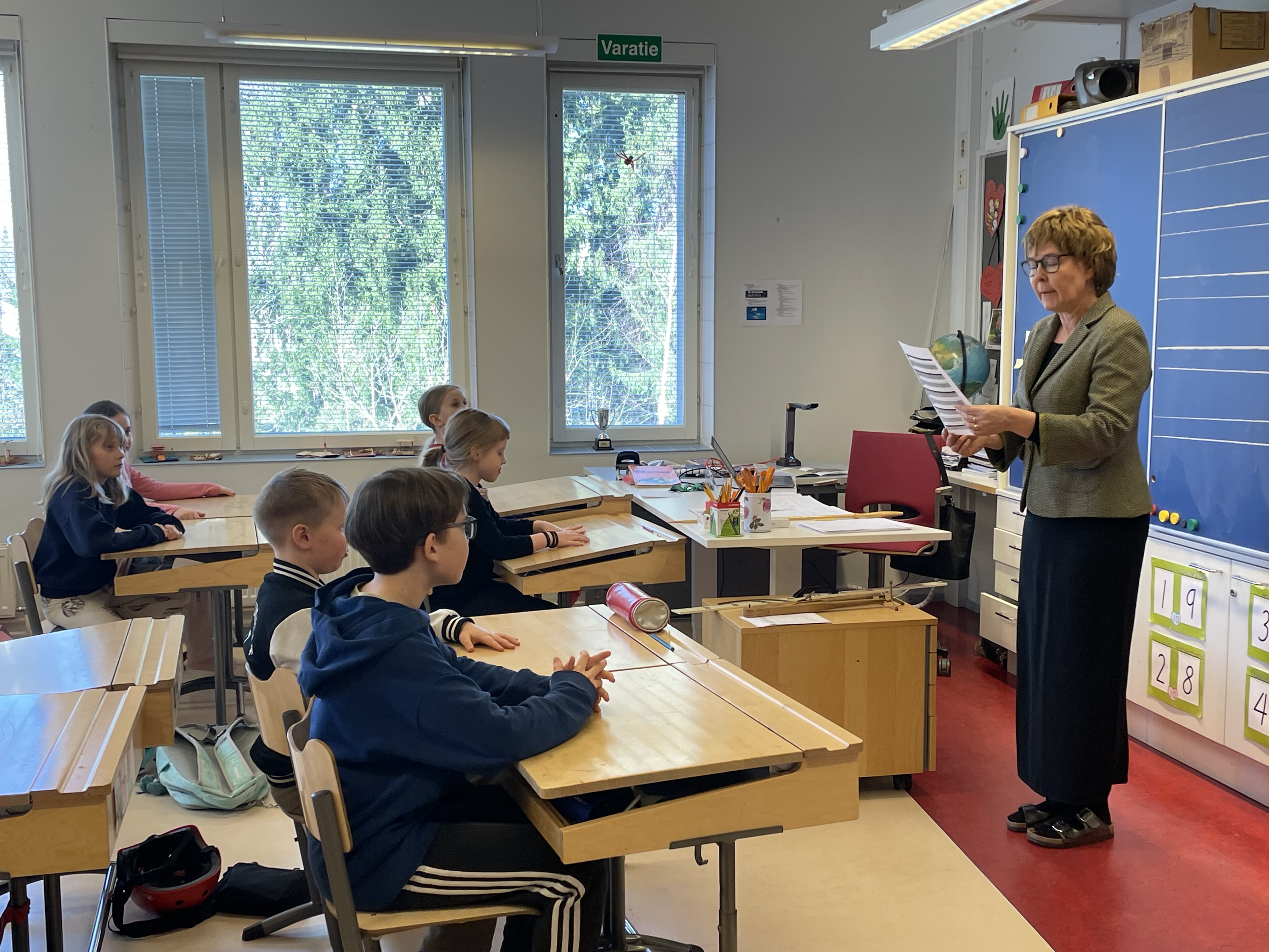 Kuvassa näkyy vanhan ajan koulun oppitunti. 