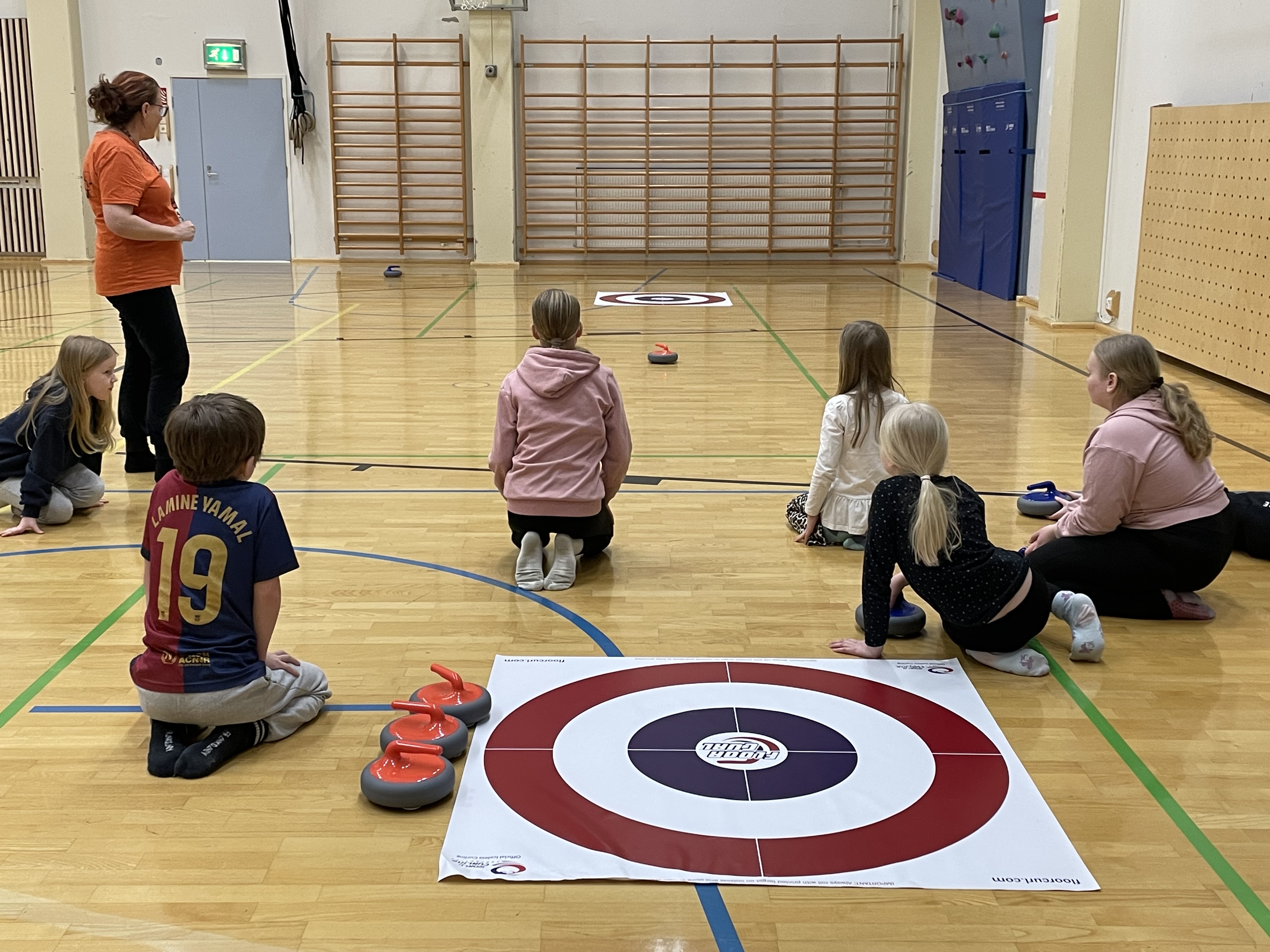 Kuvassa alakoululaisia MOK-pajassa opettelemassa curlingia. 
