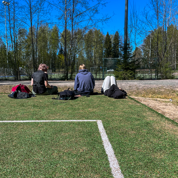 Oppilaita ottamassa aurinkoa ja lukemassa kokeisiin pihalla
