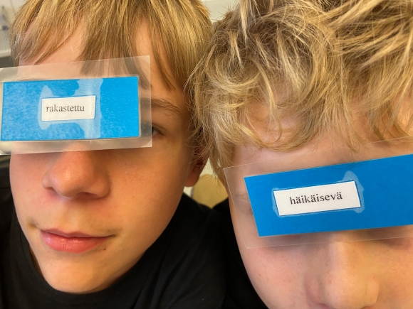 kaksi oppilasta pitää sanakortteja silmien edessä