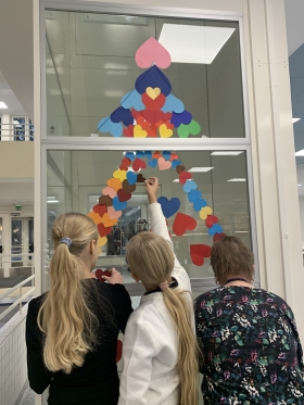 oppilaita ja ohjaaja laittamassa sydämmiä hissiin