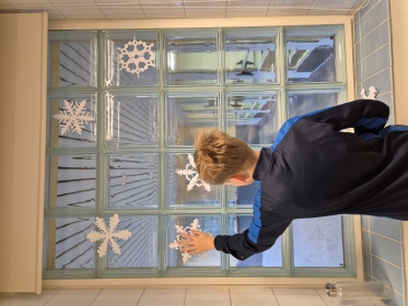 oppilas kiinnittämässä lumihiutaleita ikkunaan