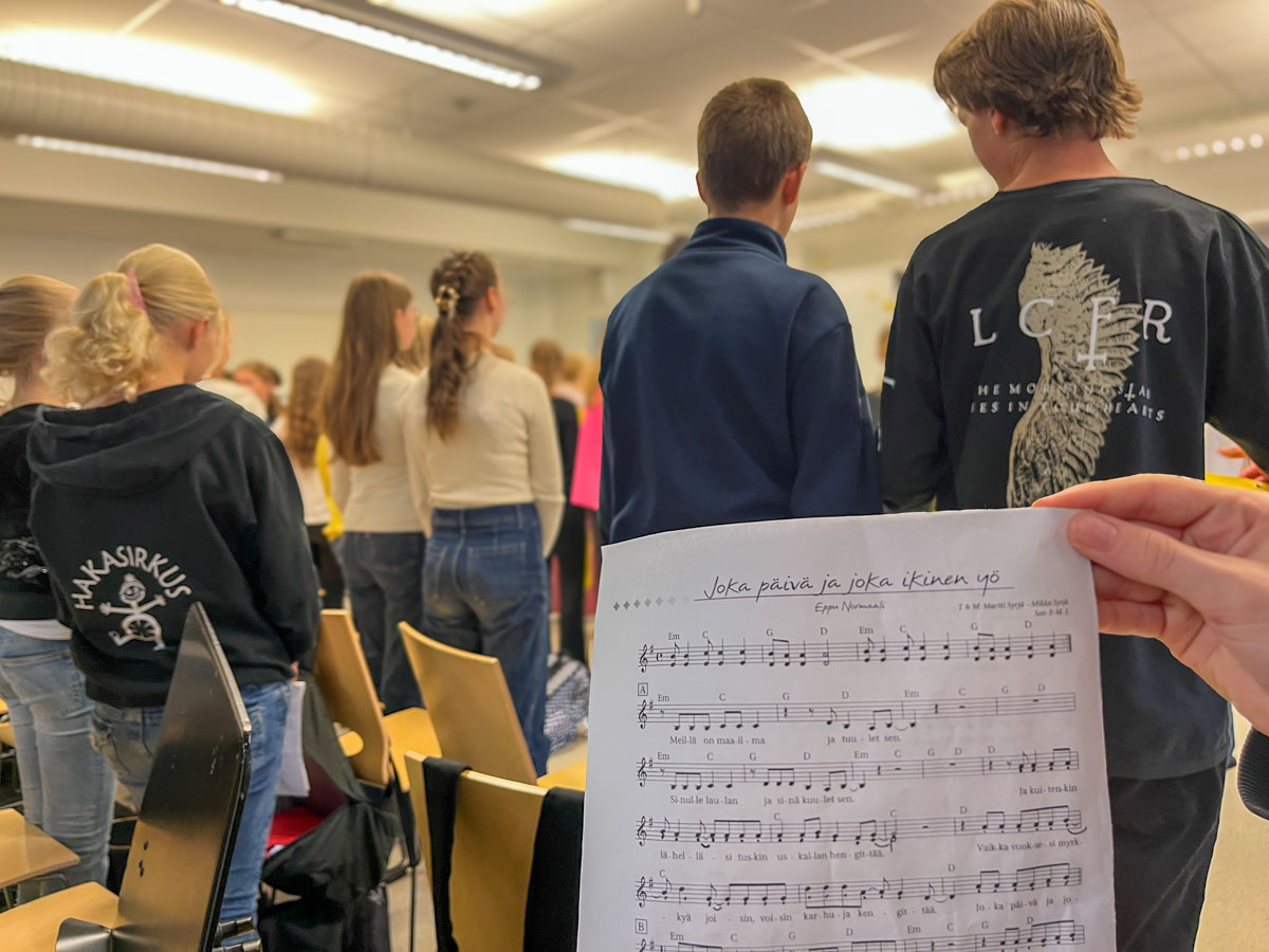 Oppilaita laulamassa musiikinluokassa, kuvassa näkyy ote nuotista