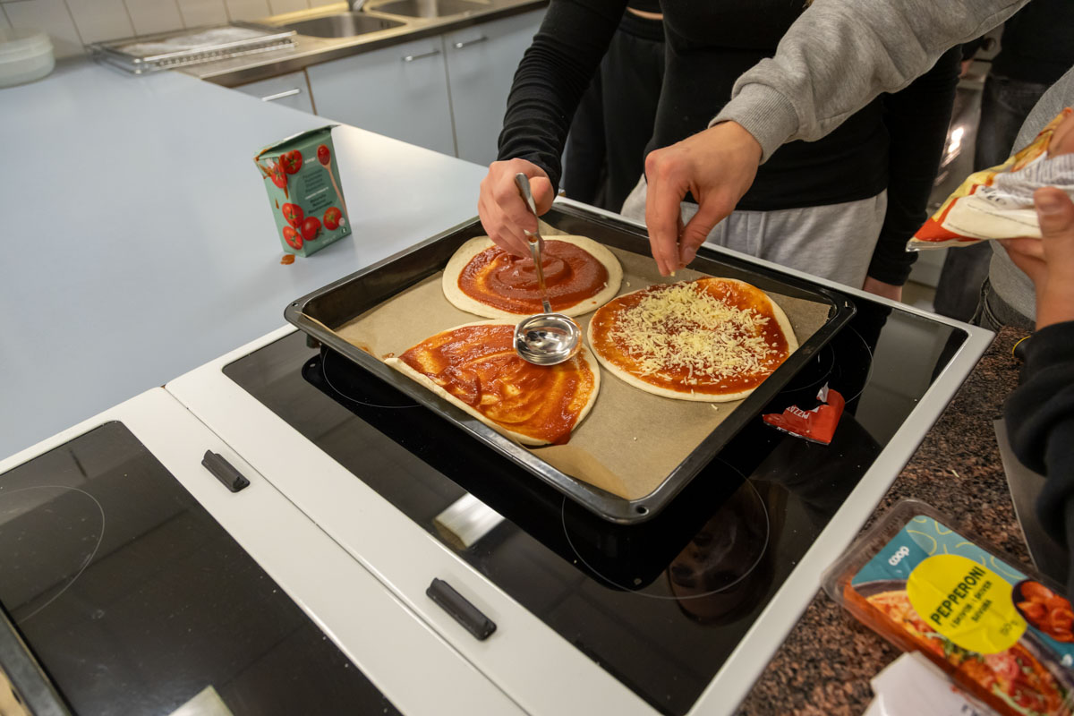 Oppilaat laittamassa pizzatäytteitä pizzaillassa