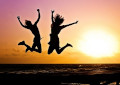 kaksi ihmistä hyppää ilmaan ja taustalla auringonlasku