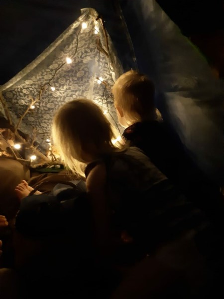 kaksi lasta istuu Hillevi-Hiiren teltassa tunnelmallisessa valaistuksessa