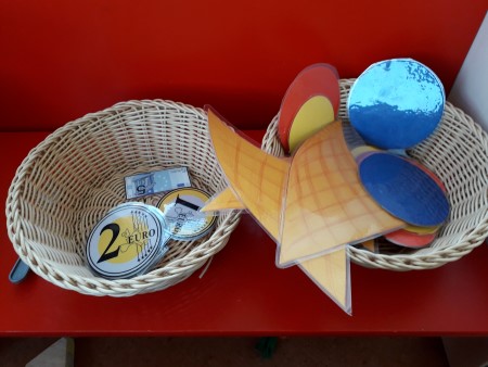 kuvassa koreihin laitetut eri jäätelöiden maut ja kori jossa on leikissä käytetyt yhden ja kahden euron rahat