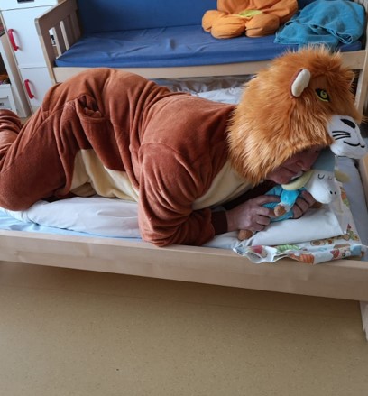 leijonan rooliasuun pukeutunut leijona nukkaa sängyssä