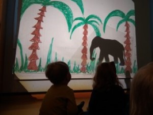 kuvassa lapsi katsoo varjoteatteriesityksen norsua