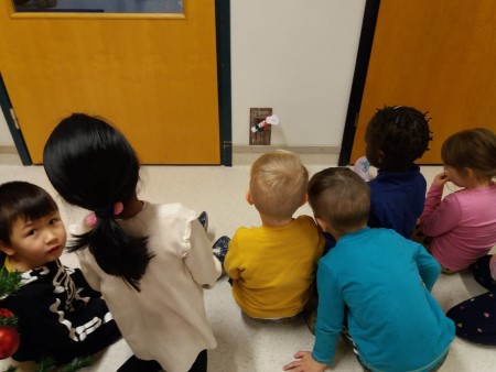 Lapset istuvat lattialla ja katsovat seinään lattian rajassa olevaa tonttuovea