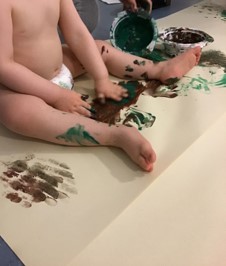 kuva lapsesta joka maalaa sormiväreillä viidakkoa