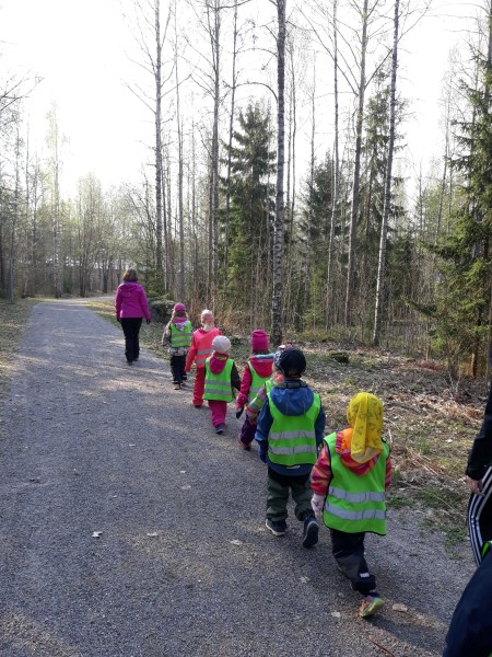 lapset kulkevat jonossa aikuisen johdolla tienvartta pitkin