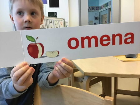 omena-sanan harjoituskortti poikanäyttää omenen kuvaa ja sanaa pahvikortissa