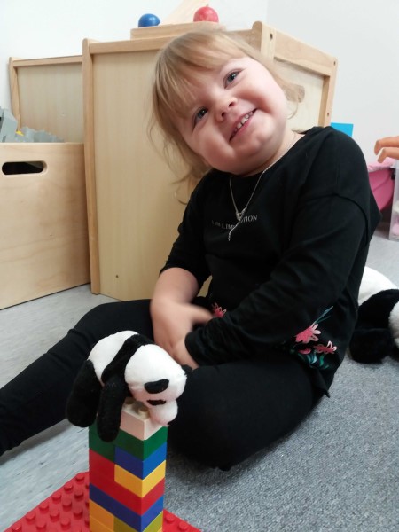 Tyttö ja pandakarhu Kuvassa on tyttö, legotorni ja pandakarhu