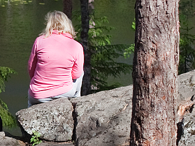 Nainen istuu kivellä kuvassa