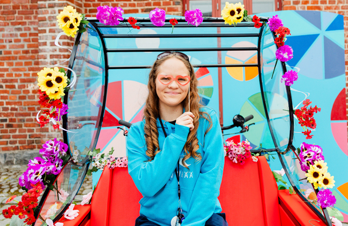 Riksakuski istuu pyöränsä päällä.